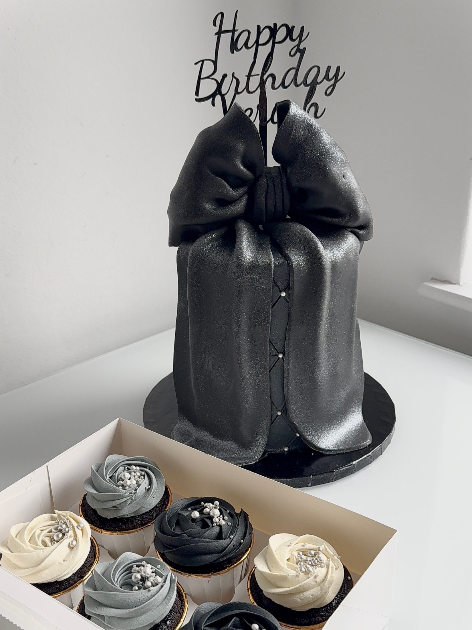 Black bow celebration cake with cupcakes